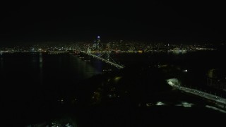AX0174_0136 - 6K stock footage aerial video ascend over Yerba Buena Island, reveal Bay Bridge and Downtown San Francisco at night, California