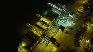 AX0174_0199 - 6K aerial stock footage passing by a cargo ship at the Port of Oakland at night, California