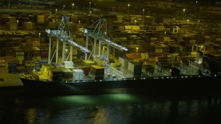 AX0174_0201 - 6K aerial stock footage flyby a cargo ship docked at the Port of Oakland at night, California