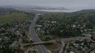 AX0175_0040 - 6K stock footage aerial video fly over Highway 101 and suburban homes in Mill Valley on a foggy day, California