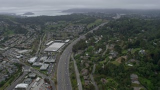 AX0175_0058 - 6K stock footage aerial video tilt from light traffic on 101 freeway through Corte Madera on a foggy day, California