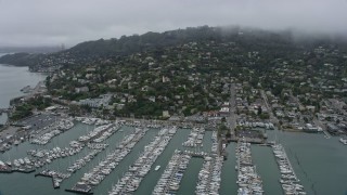 AX0175_0064 - 6K aerial stock footage of passing by Sausalito neighborhoods and marinas on a foggy day, California
