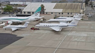 AX0175_0093 - 6K aerial stock footage of flying by private jet parked at Oakland Airport, California