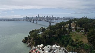 AX0175_0114 - 6K stock footage aerial video ascend over Yerba Buena Island, reveal Bay Bridge and Downtown San Francisco, California