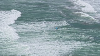AX0175_0190 - 6K aerial stock footage of a kite surfer on ocean waves near the Outer Sunset District, San Francisco, California