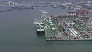 AX0175_0215 - 6K aerial stock footage of passing a cargo ship under cranes at the Port of Oakland, California