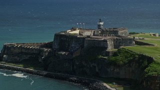 AX101_016E - 4.8K aerial stock footage of a Historic fort along the coast resting on clear blue water, Old San Juan Puerto Rico