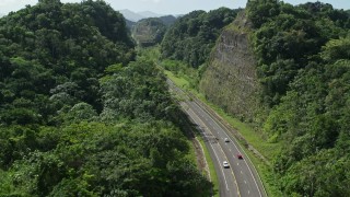 AX101_078E - 4.8K aerial stock footage Following light traffic through lush green mountains, Karst Forest, Puerto Rico