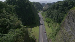 AX101_081 - 4.8K aerial stock footage Following traffic along a highway through lush green mountains, Karst Forest, Puerto Rico