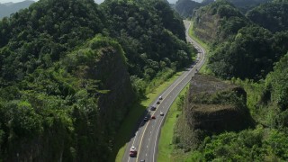AX101_081E - 4.8K aerial stock footage Following traffic along a highway through lush green mountains, Karst Forest, Puerto Rico