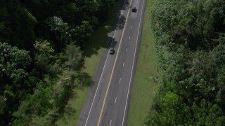 AX101_083 - 4.8K aerial stock footage Tilting up on a highway through lush green mountains, Karst Forest, Puerto Rico