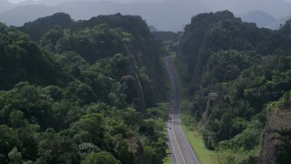 AX101_085 - 4.8K aerial stock footage Flying above highway cutting through lush green mountains, Karst Forest, Puerto Rico