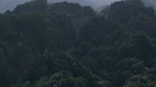 AX101_086 - 4.8K aerial stock footage Flying away from a highway cutting through lush green mountains, Karst Forest, Puerto Rico