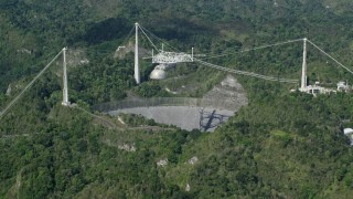 AX101_090E - 4.8K aerial stock footage revealing Arecibo Observatory among lush green forests, Puerto Rico