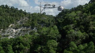 AX101_115E - 4.8K aerial stock footage Low approach above trees toward Arecibo Observatory, Puerto Rico