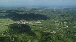 AX101_124E - 4.8K aerial stock footage of Rural homes situated among lush green trees in Karst mountains, Arecibo, Puerto Rico