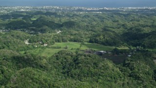 AX101_128E - 4.8K aerial stock footage Flying over tree covered hills toward the coast, Arecibo, Puerto Rico