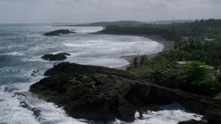 AX101_181 - 4.8K aerial stock footage of Rock formations in clear waters along a tree lined coast, Barceloneta, Puerto Rico 