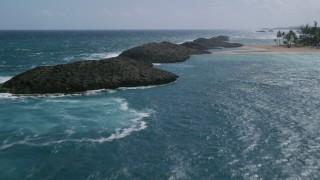 AX101_202 - 4.8K stock footage aerial video Flying low over rock formations in brilliant blue water and over a beach, Vega Baja, Puerto Rico 