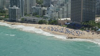 AX102_004 - 4.8K aerial stock footage of Tourists on a beach enjoying clear blue waters, San Juan, Puerto Rico