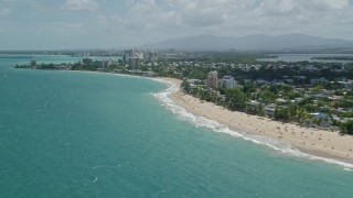 AX102_005E - 4.8K aerial stock footage of beaches and coastal community along crystal blue water, San Juan, Puerto Rico