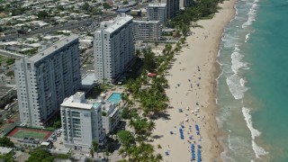 AX102_011 - 4.8K aerial stock footage of Hotels and apartment buildings along the beach and clear turquoise waters, Carolina, San Juan 