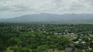 AX102_031E - 4.8K aerial stock footage of Rural neighborhoods nestled in trees near a mountain, Loiza, Puerto Rico