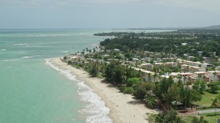 AX102_033E - 4.8K aerial stock footage of Condominiums and beachfront homes along clear turquoise waters, Loiza, Puerto Rico