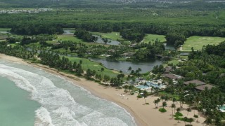 AX102_039E - 4.8K aerial stock footage of turquoise waters along the beach approaching a resort, Rio Grande, Puerto Rico