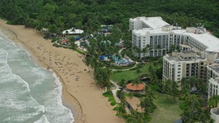 AX102_046E - 4.8K aerial stock footage of sunbathers at the oceanfront Wyndham Grand Rio Mar Beach Resort and Spa, Rio Grande, Puerto Rico