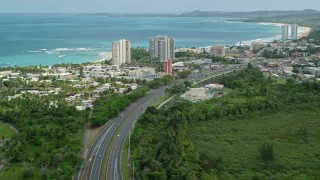 AX102_048E - 4.8K aerial stock footage highway near the beach, pan to reveal beach community, Luquillo, Puerto Rico