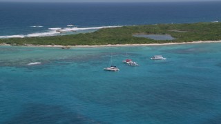 AX102_074 - 4.8K aerial stock footage of Catamarans in tropical blue waters with reefs near an island, Rada Fajardo, Puerto Rico