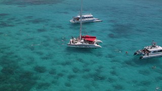 AX102_079 - 4.8K aerial stock footage Orbiting catamarans near a small island in clear blue water, Rada Fajardo, Puerto Rico 