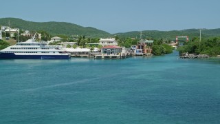 AX102_148E - 4.8K aerial stock footage of a docked ferry in sapphire blue waters by a small town, Culebra, Puerto Rico