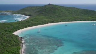AX102_182 - 4.8K aerial stock footage of Catamarans in turquoise blue waters along a white sand Caribbean beach, Culebrita, Puerto Rico 