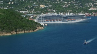 AX102_200 - 4.8K aerial stock footage of a Cruise ship docked in sapphire blue waters along a coastal town, Charlotte Amalie, St. Thomas 