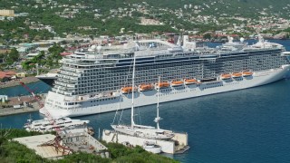AX102_201E - 4.8K aerial stock footage fly over coastal hill, reveal docked cruise ship in a coastal town, Charlotte Amalie, St. Thomas