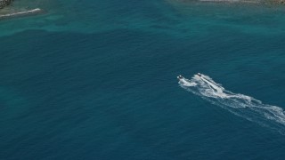 AX102_206 - 4.8K aerial stock footage of Jet skiers in sapphire waters to reveal coastal town, Charlotte Amalie, St. Thomas