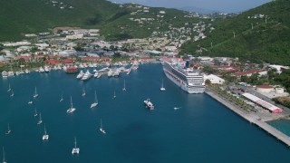 AX102_209 - 4.8K aerial stock footage of a Cruise ship and yachts in sapphire waters along a coastal town, Charlotte Amalie, St. Thomas 