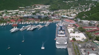 AX102_210 - 4.8K aerial stock footage of a Cruise ship and yachts docked in sapphire waters along a coastal town, Charlotte Amalie, St. Thomas 