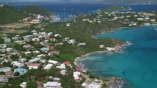 AX102_240 - 4.8K aerial stock footage Flying over trees and homes surrounded by sapphire blue waters, Red Hook, St Thomas