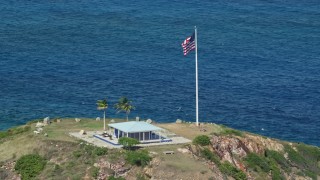 AX102_251 - 4.8K stock footage aerial video Orbiting an oceanfront guesthouse and American flag, Little St James Island, St Thomas