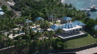AX102_253 - 4.8K stock footage aerial video of an Oceanfront mansion and palm trees on turquoise blue waters, Little St James Island, St Thomas