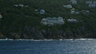 AX102_262E - 4.8K aerial stock footage of a hillside oceanfront homes along sapphire waters, Northside, St Thomas