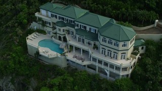 AX102_264E - 4.8K aerial stock footage of a hillside oceanfront mansion with a pool, Northside, St Thomas