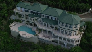 AX102_265 - 4.8K aerial stock footage of a Hillside oceanfront mansion and sapphire blue waters, Northside, St Thomas 