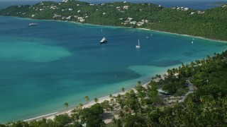 AX102_272E - 4.8K aerial stock footage of white sand Caribbean beach along turquoise blue waters with sailboats, Magens Bay, St Thomas