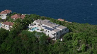 AX102_286 - 4.8K aerial stock footage of a Hilltop mansion overlooking turquoise blue Caribbean waters, Magens Bay, St Thomas