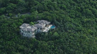 AX102_290 - 4.8K aerial stock footage of Hillside mansion surrounded by trees, Northside, St Thomas 