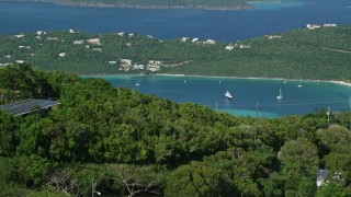 AX102_300E - 4.8K aerial stock footage of a Caribbean beach and tree covered hillside by turquoise blue waters, Magens Bay, St Thomas